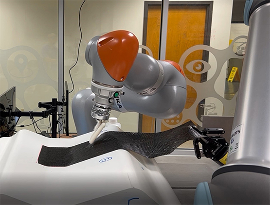 wo collaborative robots work to autonomously layup a ply of composite material