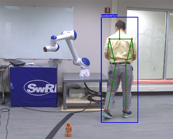 man with markerless motion capture overlayed walking through workcell with robot