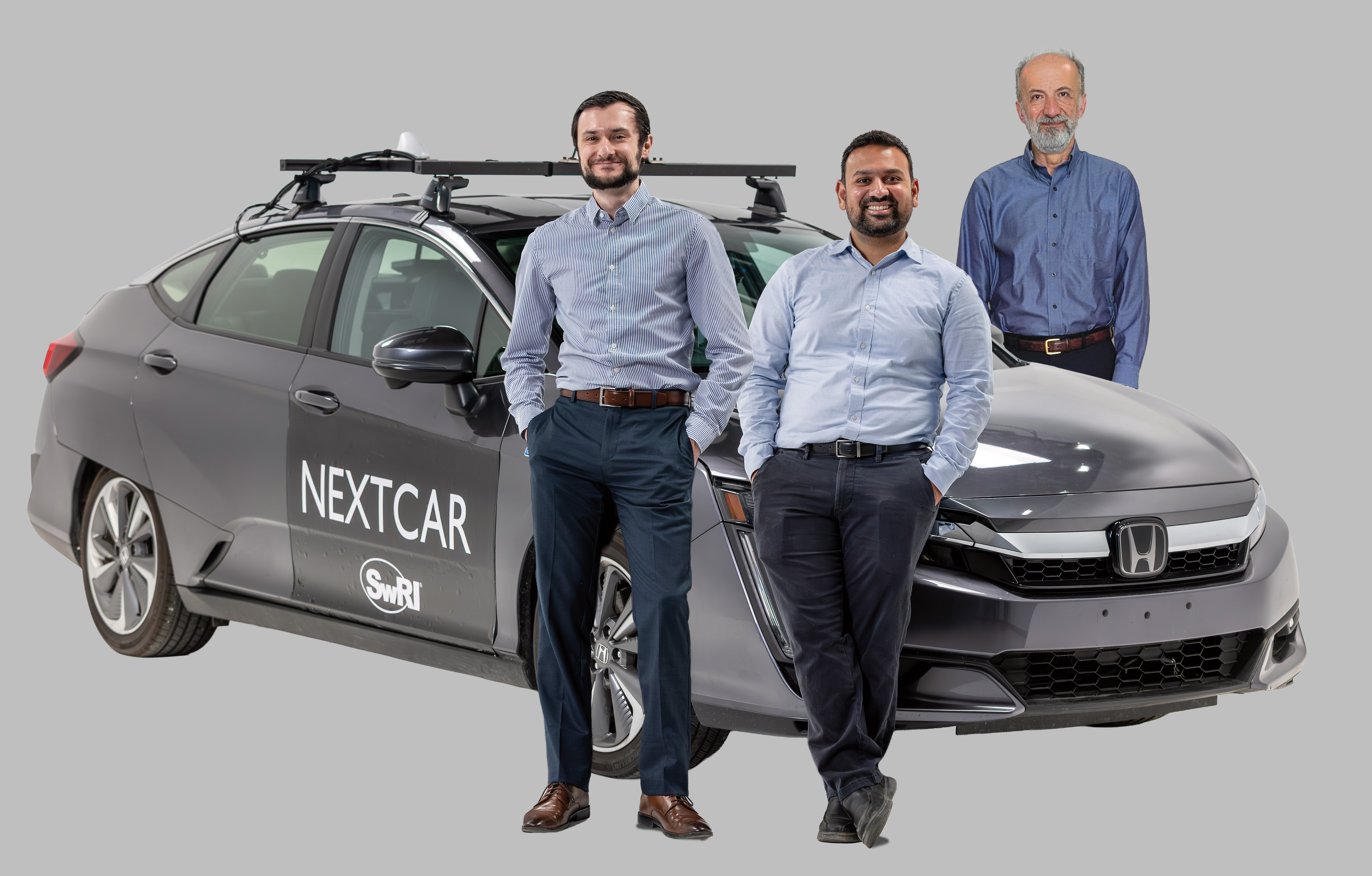Stas Gankov (left), Piyush Bhagdikar (middle), and Dr. Mrdjan Jankovic leaning against SwRI's NEXTCAR vehicle