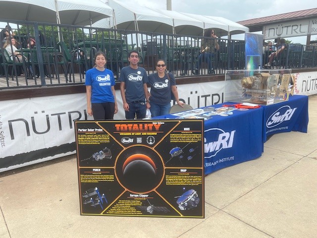 Figure 4. Umer Salman (D15), Valerie Avila (D15) and another staff member sharing information about SwRI in space at the Wolff Stadium during the total eclipse on April 8, 2024. 