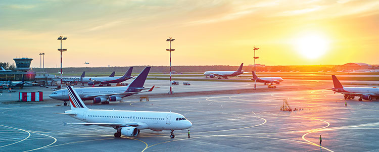 Modern airport at sunset with several aircraft on the runway