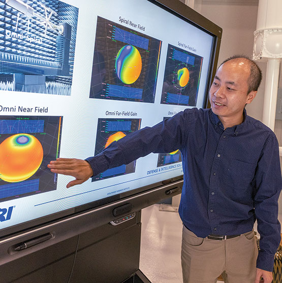A man stands next to a monitor showing off different examples of far field data on the screen.