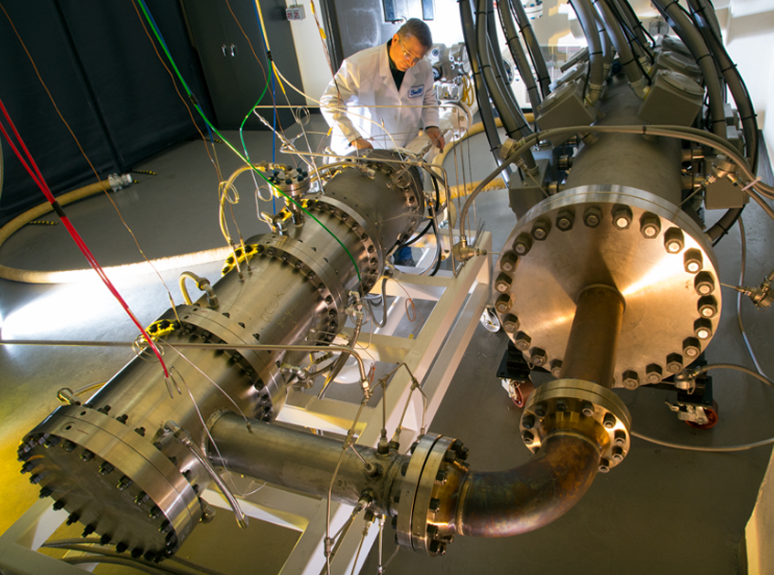 Man in lab coat checking on the high-inlet-temperature combustion test device