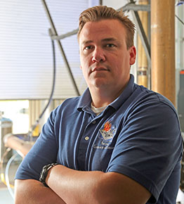 Cary Henry standing with arms crossed in a blue shirt