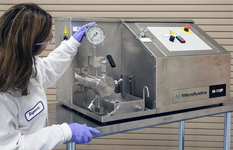 Woman wearing lab coat, checking a gauge on a high-shear mixer, which is used to reduce or disperse particles to a uniform size