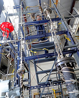 Blue scaffolding with equipment mounted to it with a technician working on top 