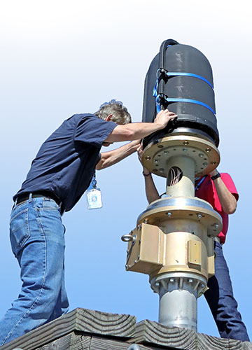 Two people adjusting an upright antenna