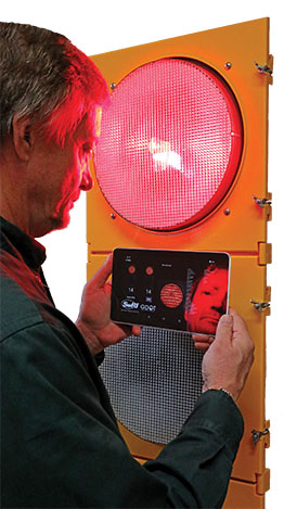 Yellow traffic signal with a person holding a tablet with traffic warnings