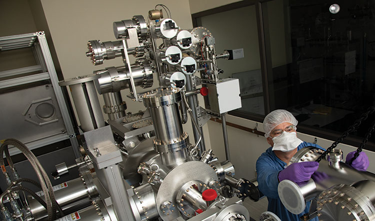 Metallic instrument in a laboratory with a technician standing by