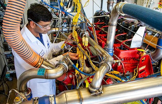 Engineer monitoring a D-EGR engine colored red with wires running from the engine to various sensors