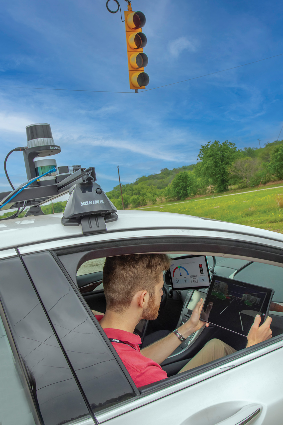 Outside of NEXTCAR, which is on a SwRI track, looking into passenger seat with SwRI staff in passenger seat with iPad