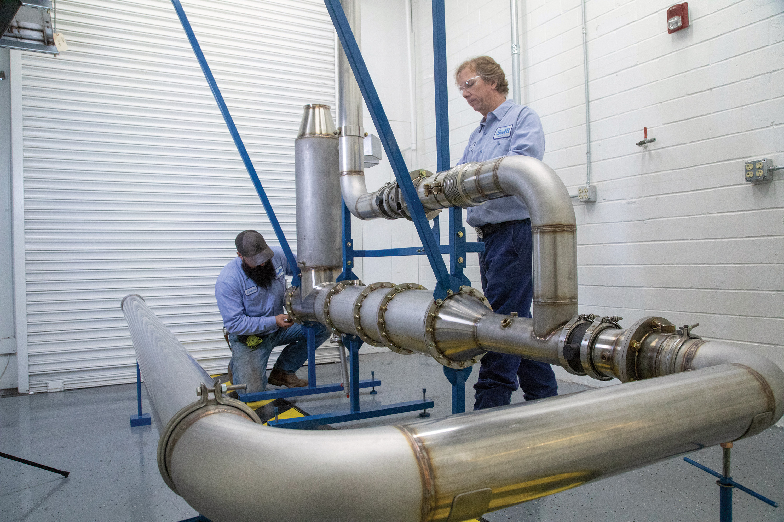 Two staff members working on piping at SwRI using CAT-DEF technology