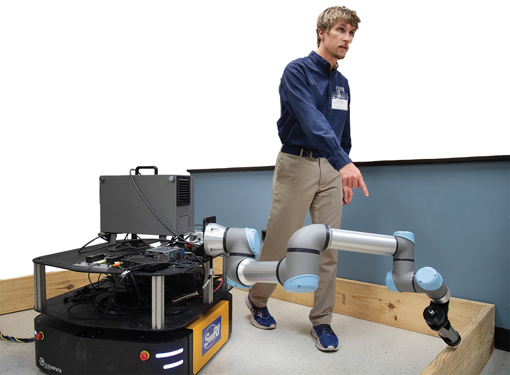 SwRI employee demonstrating using a mobile platform with a robotic arm