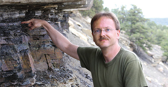 Dan Durda pointing towards a rock cliff