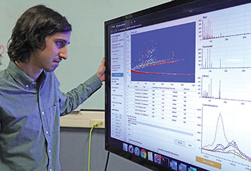 A scientist reviews data on a large monitor in front of him.