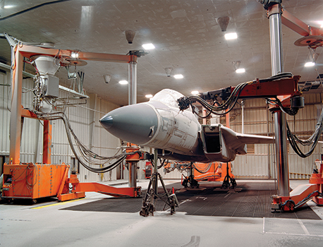 Large mobile orange robot working on an aircraft in a lab