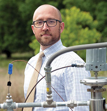 Griffin Beck standing behind metal piping 