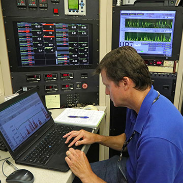 Analyst monitoring graphs of data on three screens