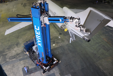 Blue robot comprised of two segments - the first is vertical with XYREC in white lettering; the second is horizontal to the ground with a laser attached. The robot is using a laser to remove an aircraft coating