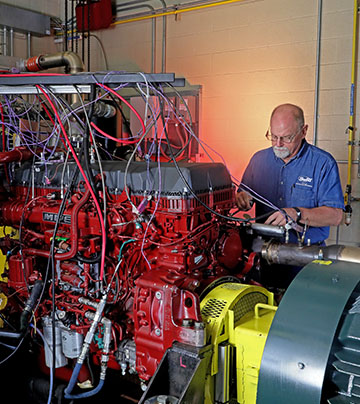 Technician standing behind a large red automotive test cell