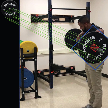 A person lifting a barbell with the software tracking the motion of the barbell plate