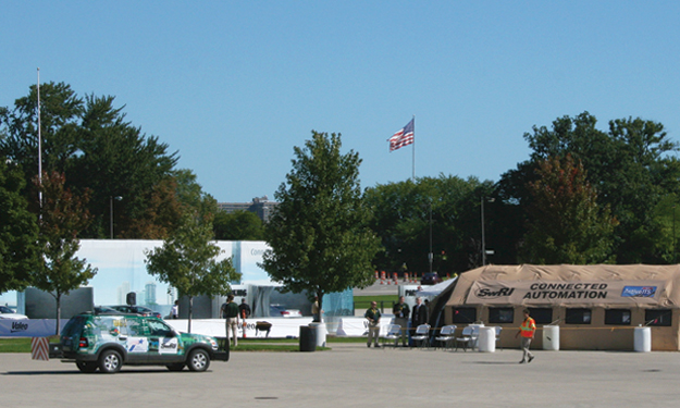 SwRI autonomous vehicle sitting in parking lot near brown tent with sign reading SwRI Connected Automation