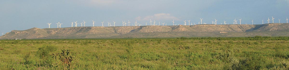 Panoramic of a mesa in the distance with many windmills on top.