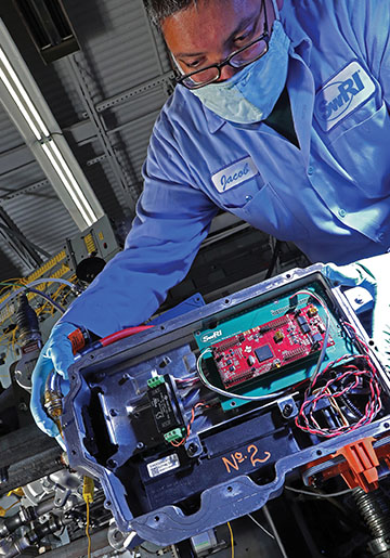An opened inverter case with electrical components visible with an engineer looking on