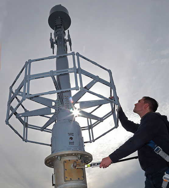 Mast antenna in the air with a technician working beside it