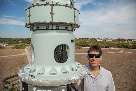 Patrick Siemsen in a grey shirt standing next to a cylindrical continuous-slot antenna array