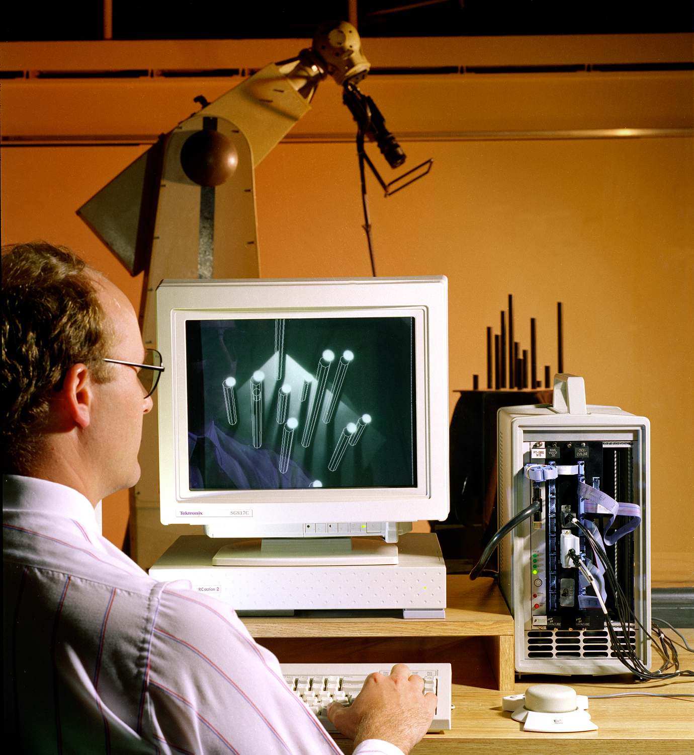 Man sitting in front of computer with robotic arm reaching down