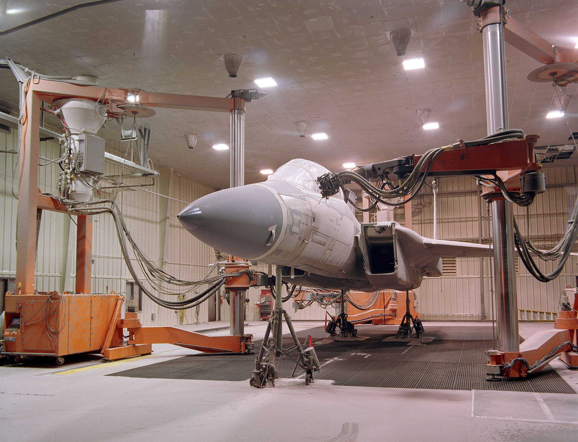 Large orange robots removing coatings from an F-15 aircraft