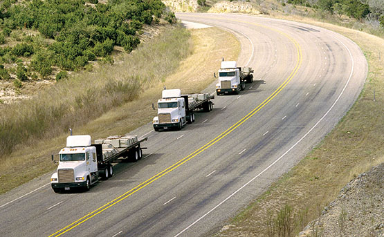 Semi-truck convoy on a hilly road