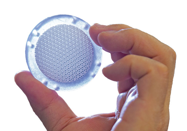 Small, translucent disc held between two fingers 