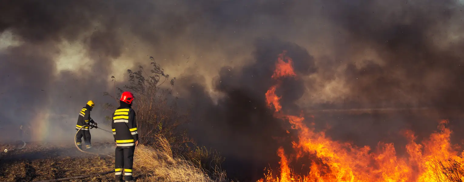 Two firefighters battling a massive wildfire