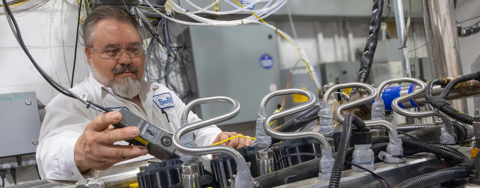 SwRI staff working on powertrain engine in SwRI lab