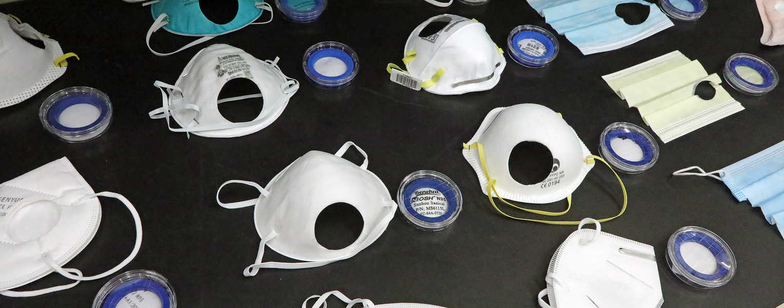 Several different colors and types of masks laid out on a table for testing