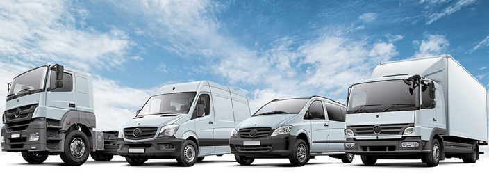 From left to right, a white semi cab, a white van, a white minivan, and a white box truck silhouetted against a blue cloudy sky