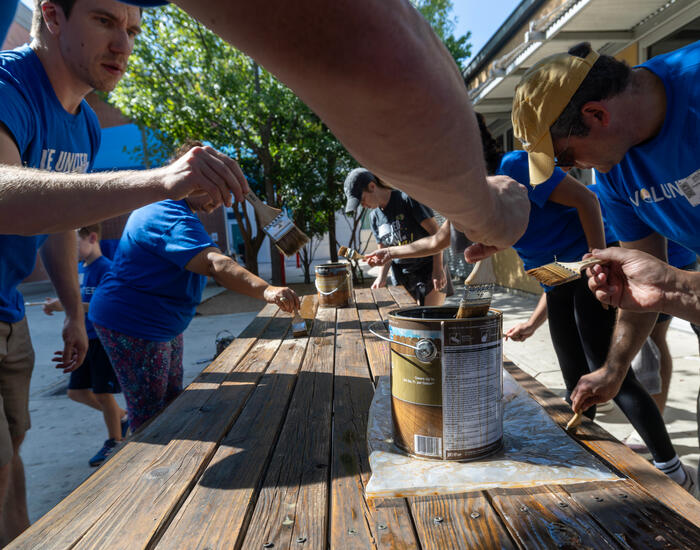 SwRI staff members surrounding a picnic table revarnishing at Haven for Hope
