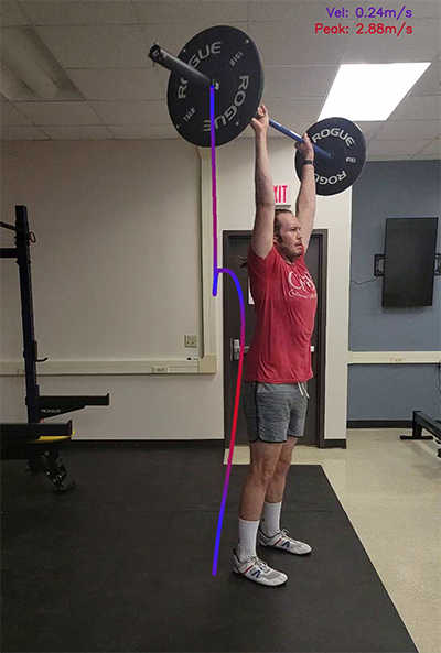 man holding olympic barbell overhead with path of barbell being lifted overlayed