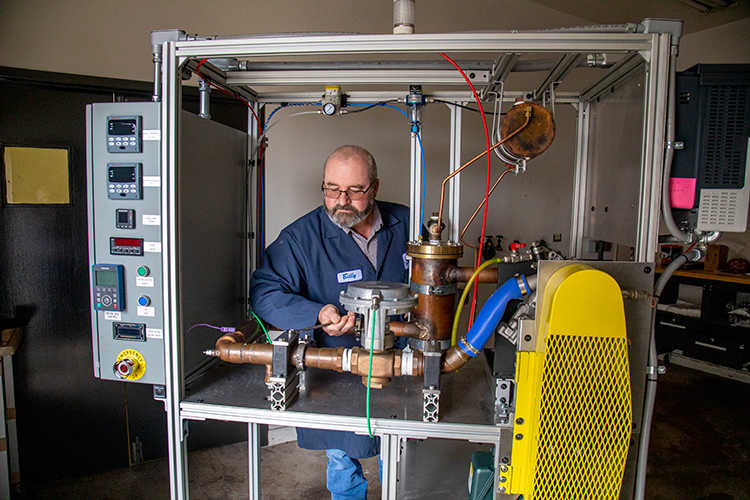 man in blue lab coat adjusting SwRI-designed and built ASTM D2809 cavitation rig