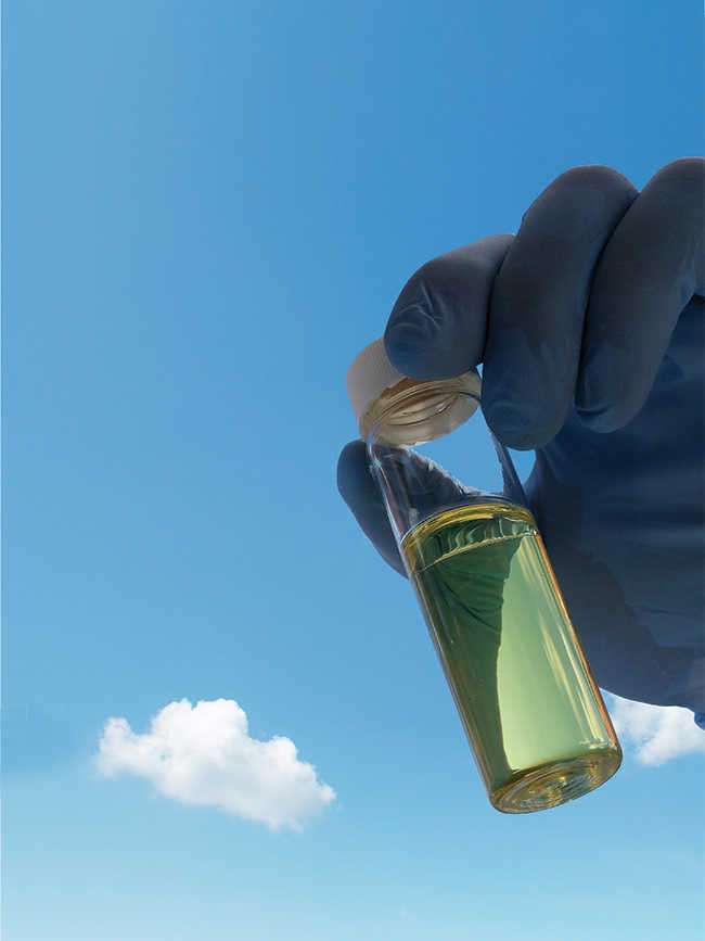 blue gloved hand holding vial of diesel fuel