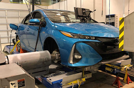 A blue Prius is set up in a shop and connected to SwRI’s connected and automated vehicle chassis dynamometer.
