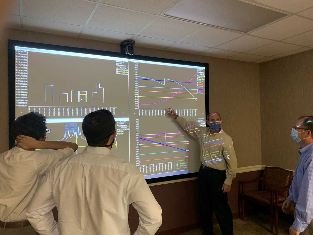 Engineers discussing data in front of a projection screen