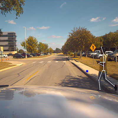 Windshield view of a person crossing a street with a skeletal overlay on the person's body