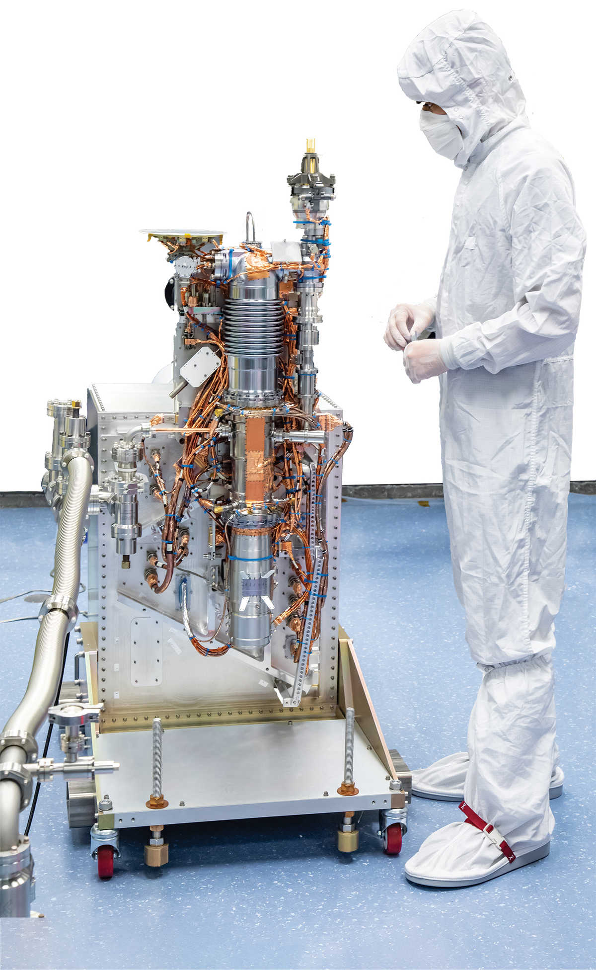 scientist in clean suit standing next to MAss Spectrometer for Planetary EXploration (MASPEX) instrument