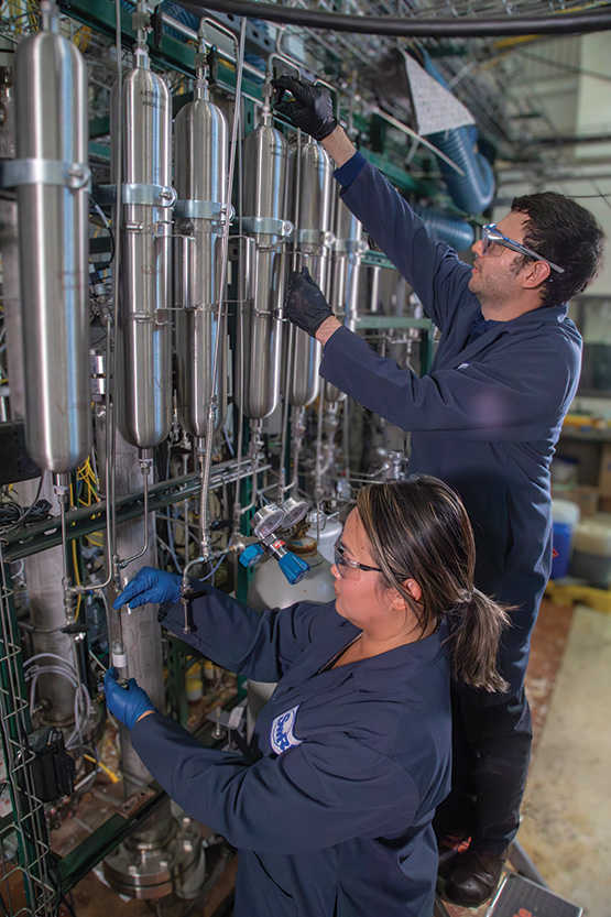 Two technicians work on refinery tubes.