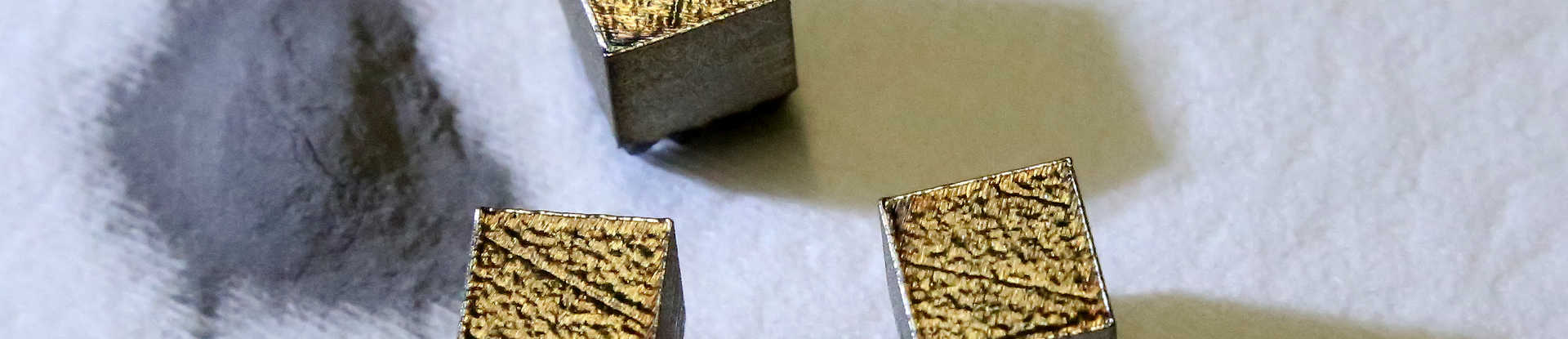 Metal powder in a pile on the left, three small metal cubes on the right