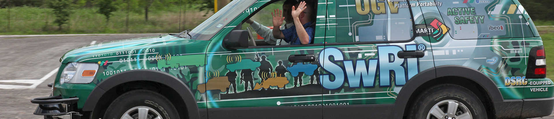 Driver with hand off steering wheel of SUV covered in vinyl graphics