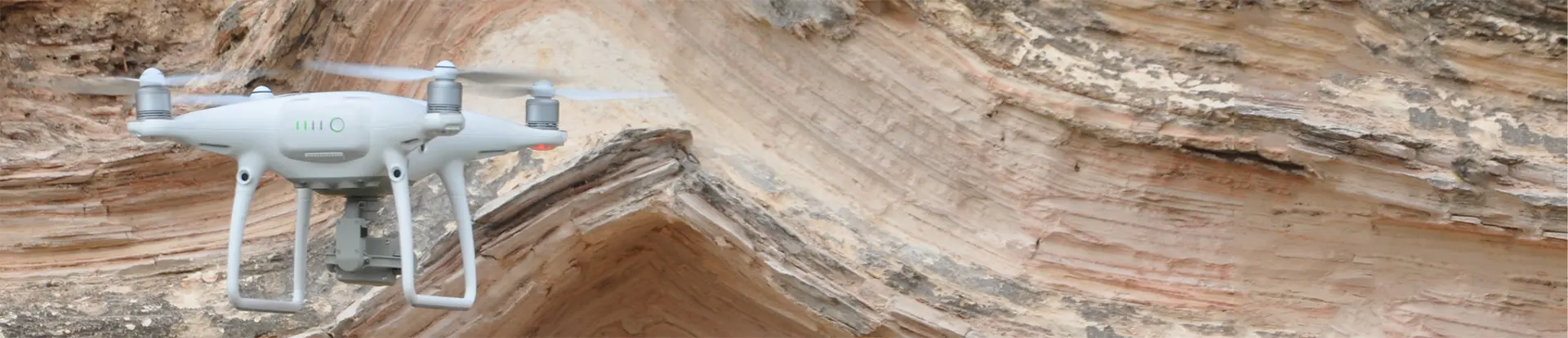A drone floating next to a rock wall
